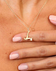 Gold necklace with L pendant worn by a person