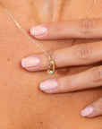 Gold necklace with a small pendant on a hand against a skin background