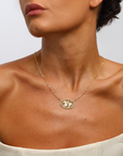 Gold necklace with lion worn by a marilisi model on a neutral background