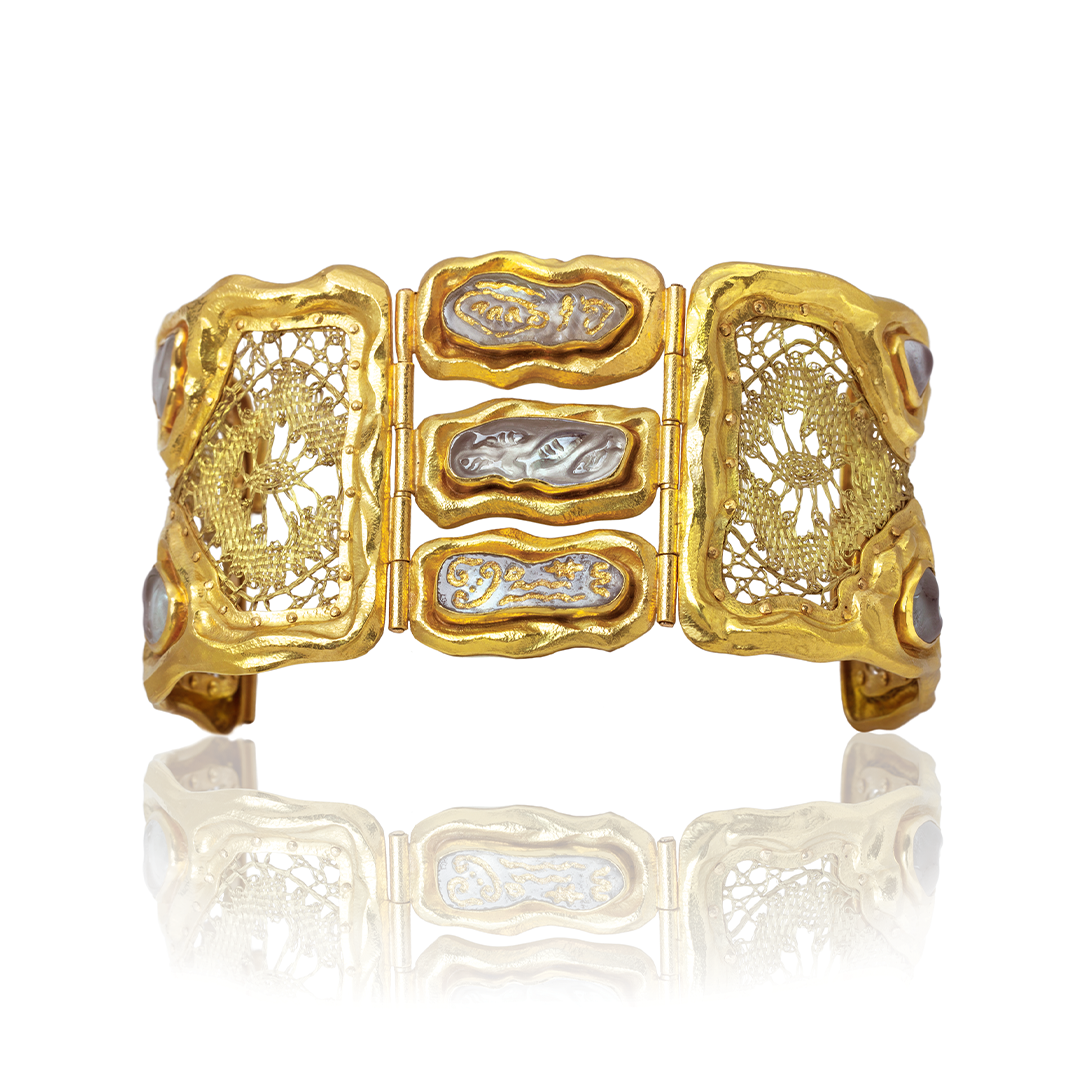 Gold bracelet with intricate designs on a white background