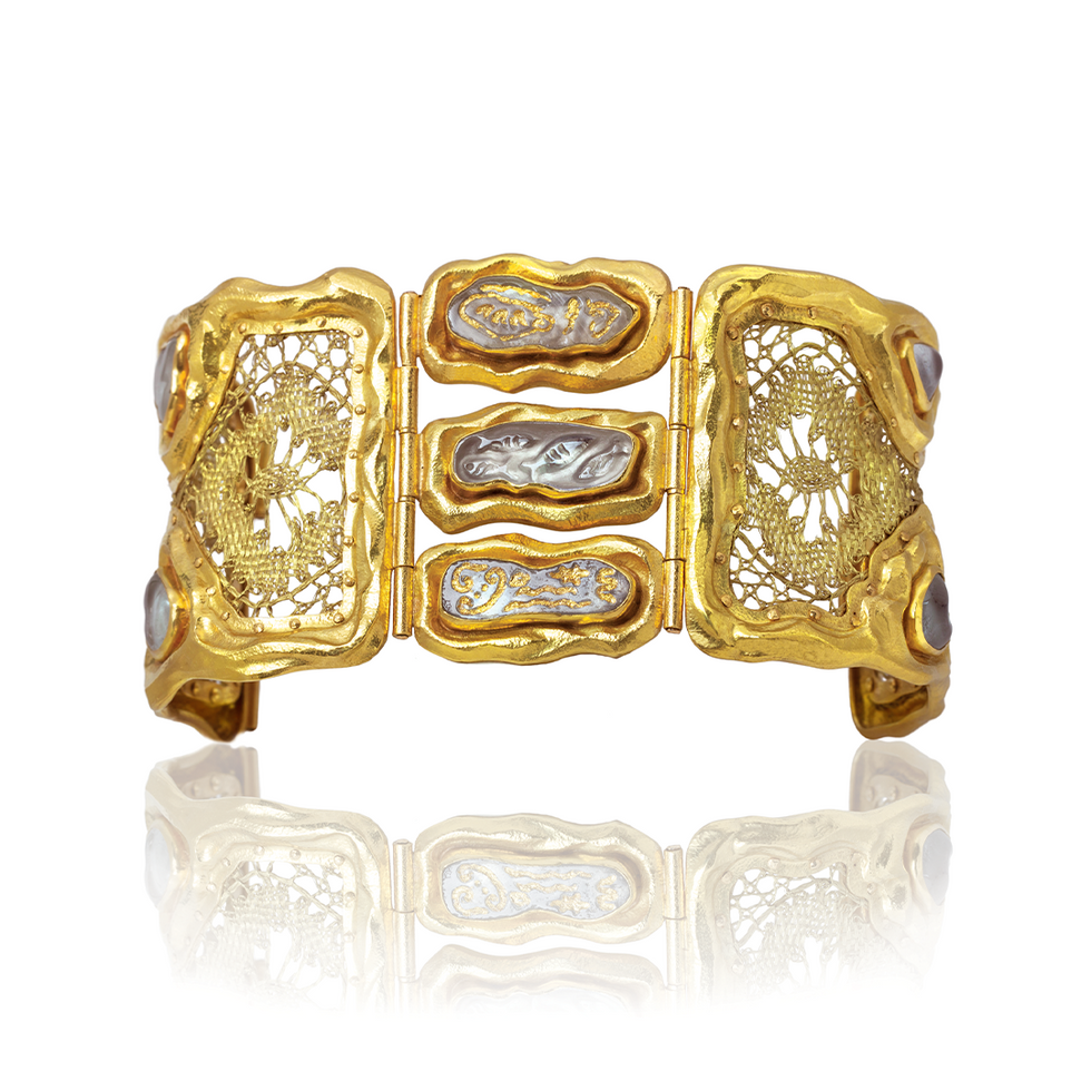 Gold bracelet with intricate designs on a white background