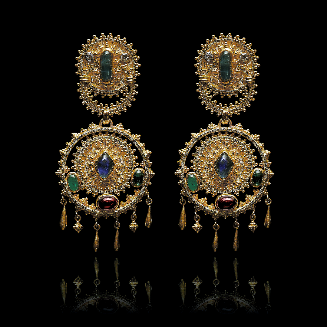 Ornate gold earrings with gemstones on a black background