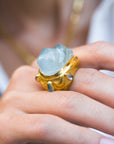Close-up of a hand wearing a large ring with a blue gemstone.