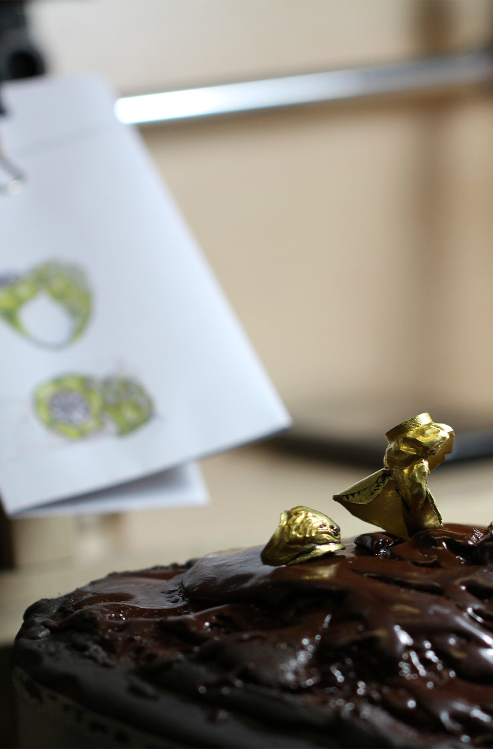 Detail of work behind the scenes. The picture shows half finished gold jewel and its sketch in the background.