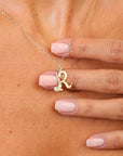 Gold necklace with a 'R' pendant on a person's neck