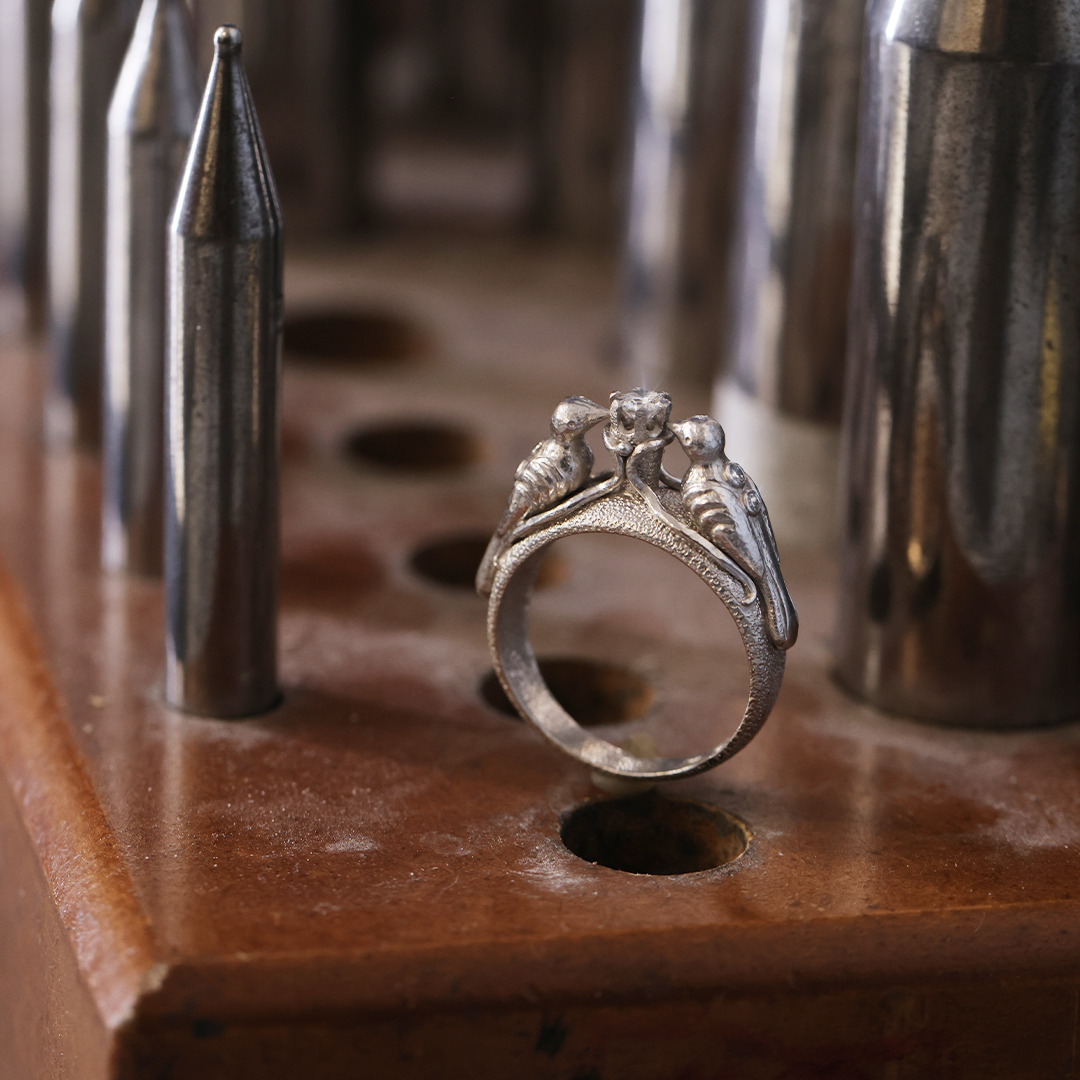 Behind the scenes at Marilisi Jewelry Atelier, featuring a handcrafted white gold artisan ring with sculptural bird motifs and diamond accents. Fine jewelry craftsmanship and traditional goldsmithing tools.
