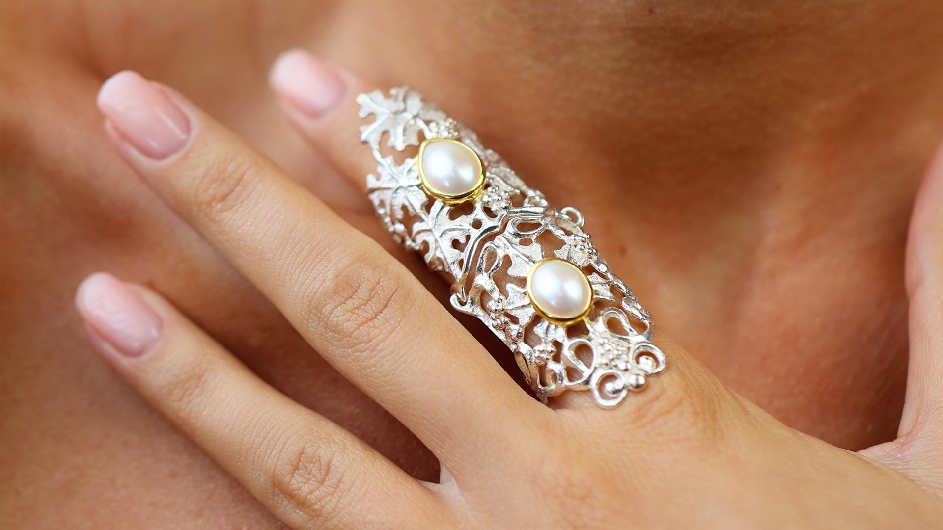 Silver ring with pearl stones on a finger