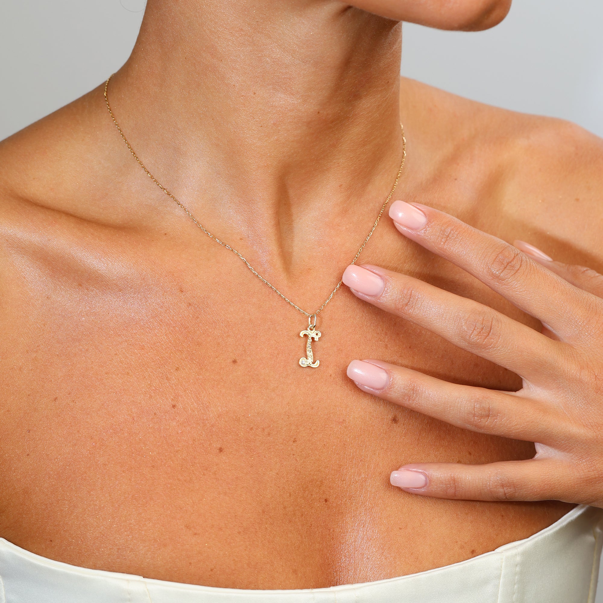 Gold necklace with a letter 'I' pendant on a person's neck