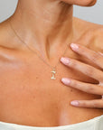 Gold necklace with a letter 'I' pendant on a person's neck