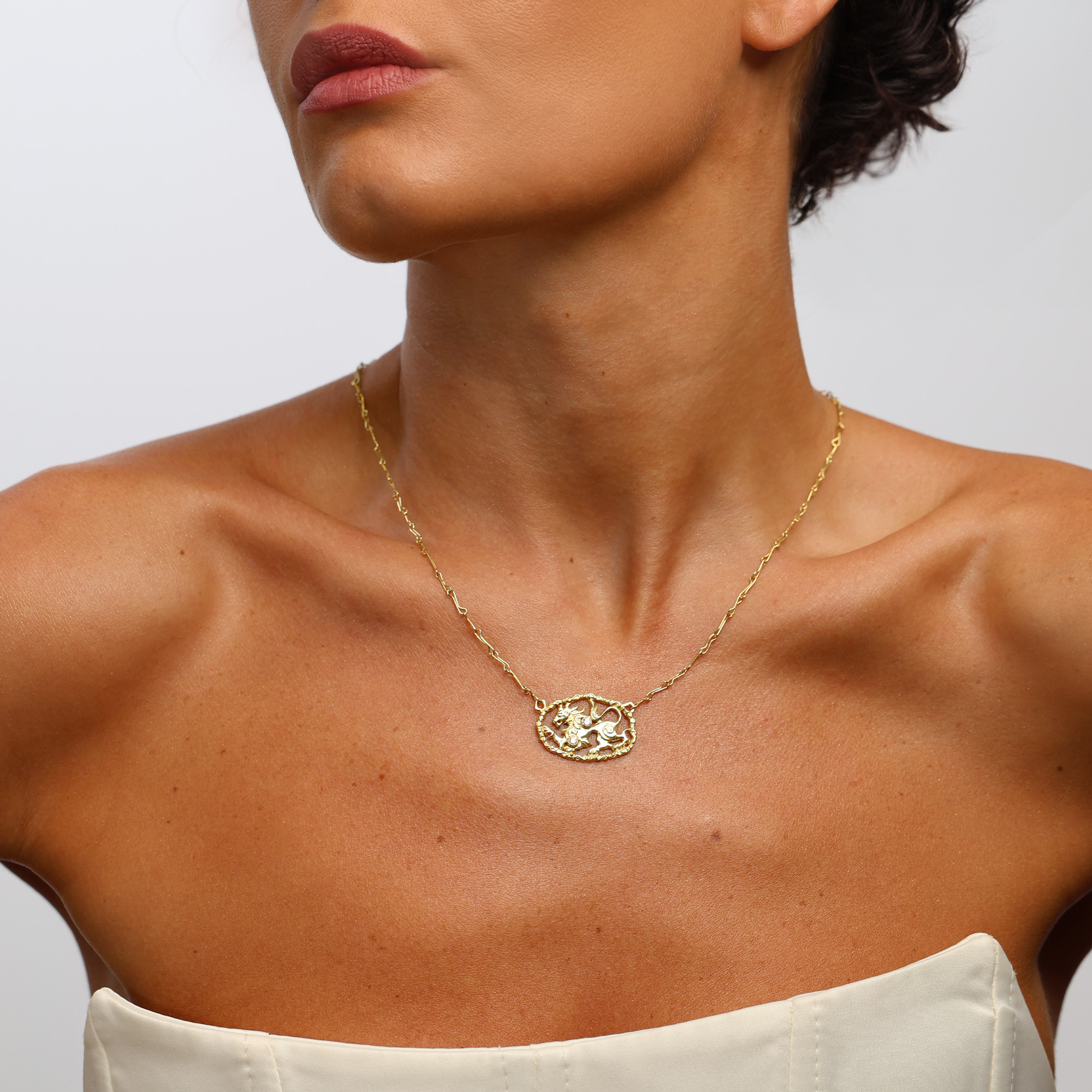 Gold necklace with lion worn by a marilisi model on a neutral background
