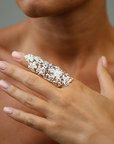 Close-up of a hand wearing an ornate silver ring against a neutral background
