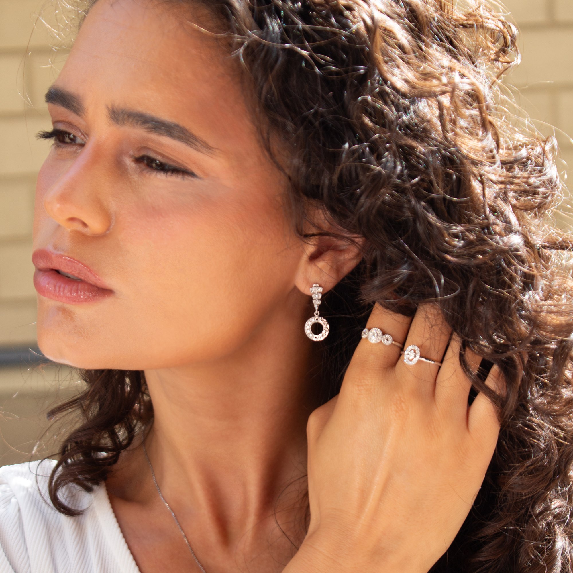 Woman wearing diamond earrings and ring, close-up of face and hand