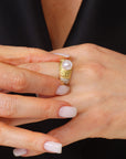 Close-up of a hand wearing a gold ring with a pearl on a black background